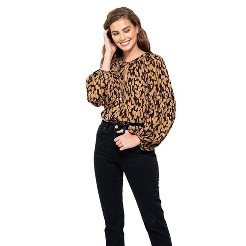 Woman wearing a leopard print blouse and black pants on a white background
