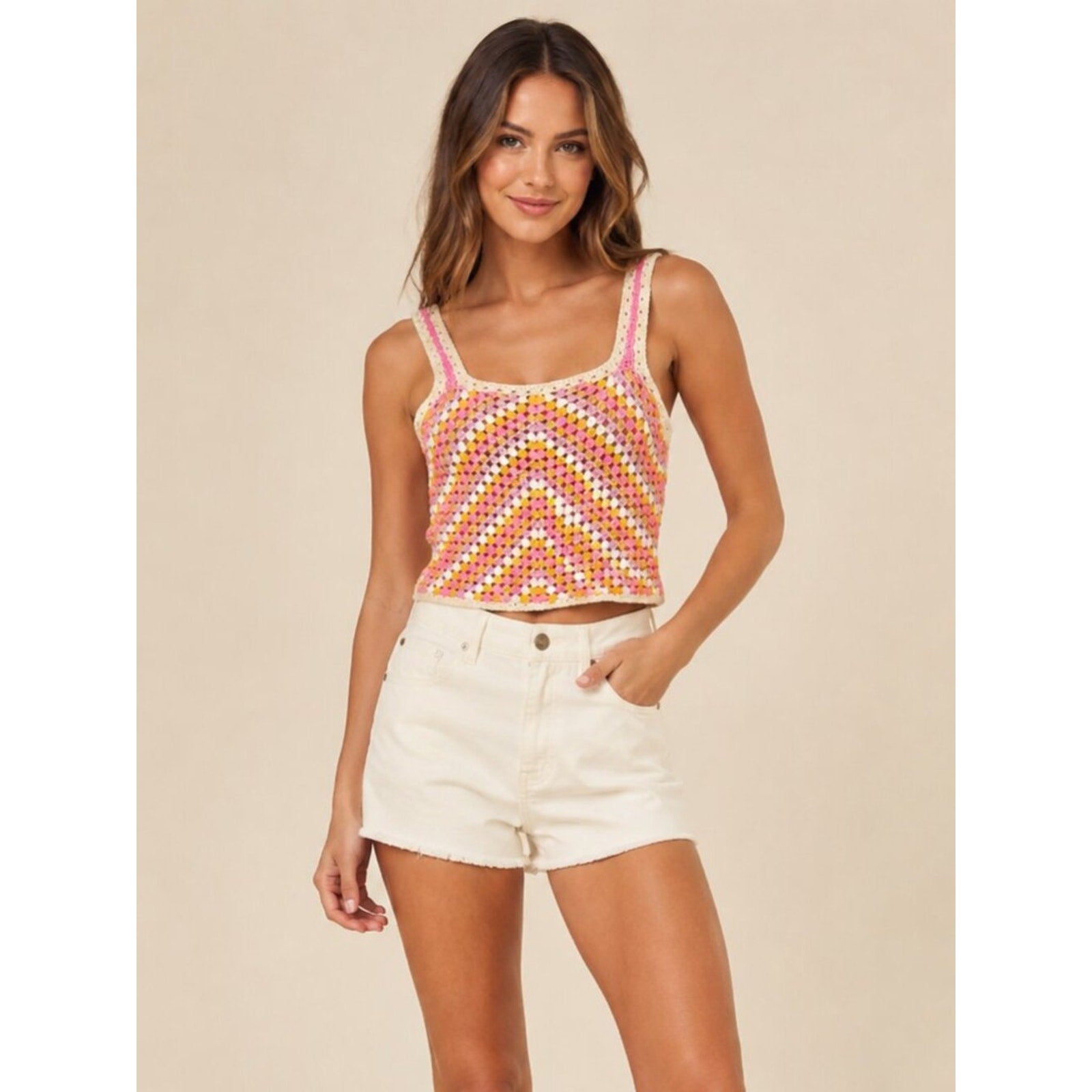 Woman wearing a colorful tank top and white shorts on a beige background