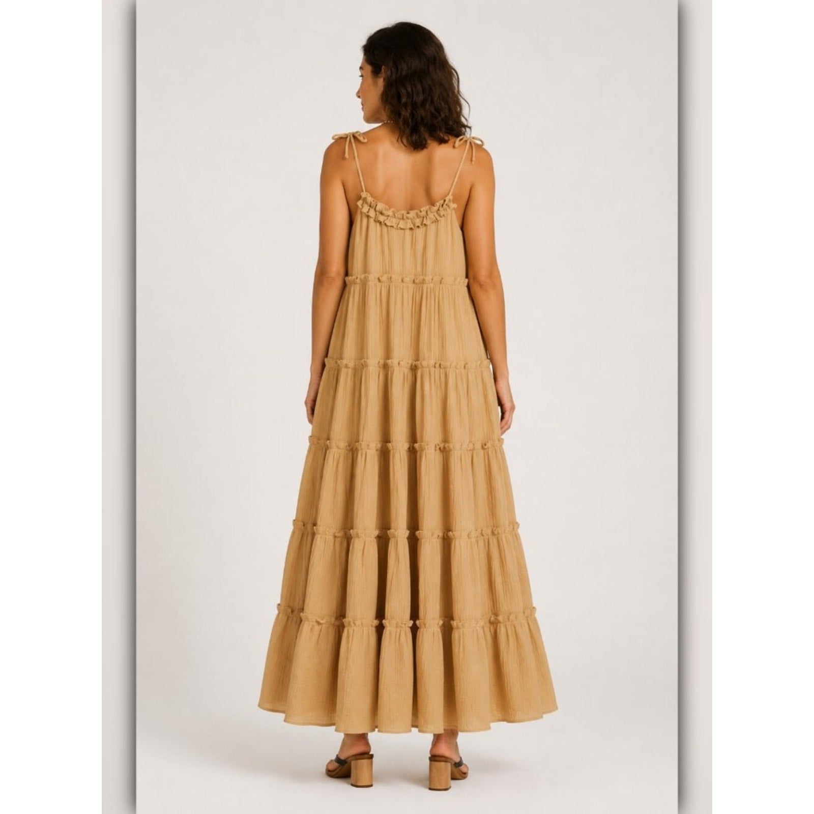 Woman wearing a beige tiered dress on a white background