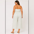 Woman wearing a strapless floral jumpsuit on a plain background