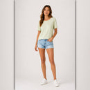 Woman wearing a light green t-shirt and denim shorts on a white background