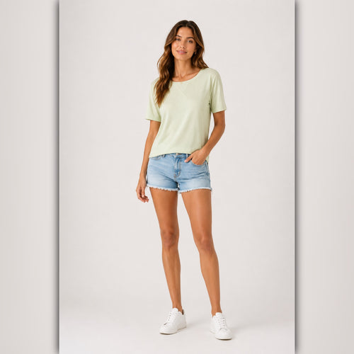 Woman wearing a light green t-shirt and denim shorts on a white background