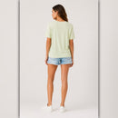 Woman wearing a light green t-shirt and denim shorts on a white background