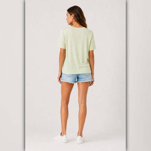 Woman wearing a light green t-shirt and denim shorts on a white background