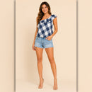 Woman wearing a blue and white checkered top and denim shorts on a beige background