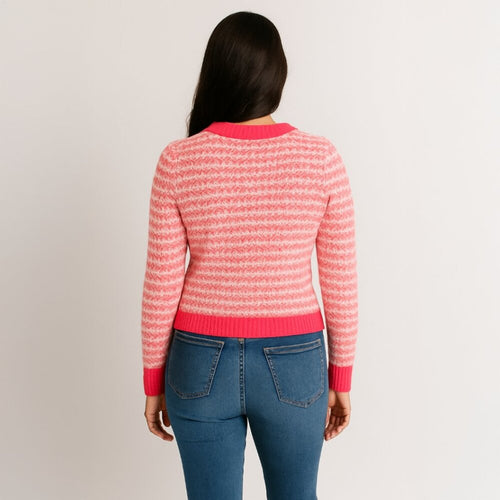 Person wearing a pink and red striped sweater with blue jeans on a plain background