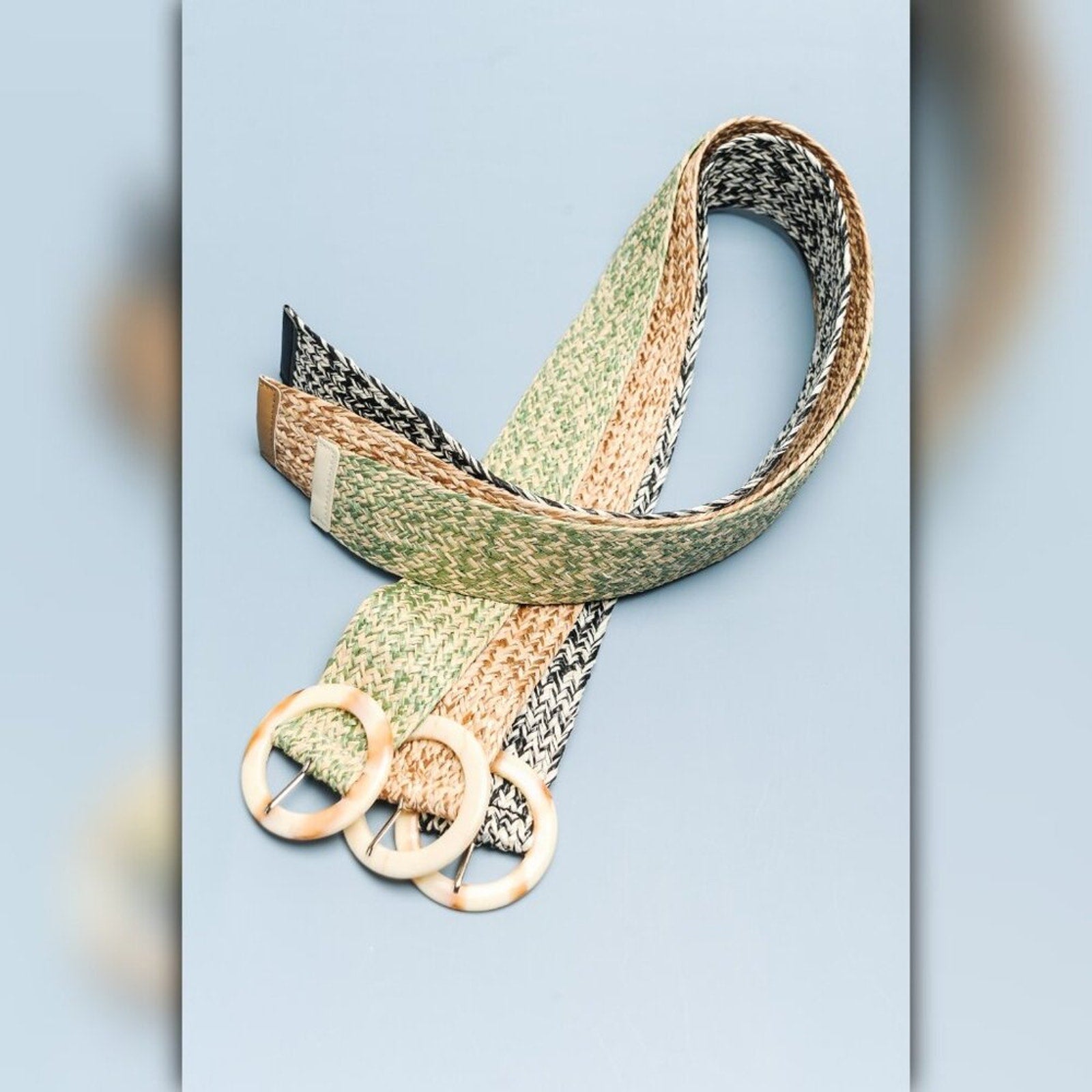 Woven belt with gold hardware on a light blue background