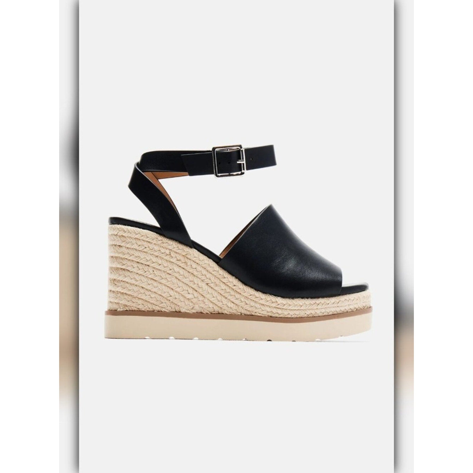 A single women's wedge sandal with a black leather peep toe, adjustable ankle strap with a silver buckle, and a thick braided jute wedge heel with a cream-colored platform sole, shown against a light gray background.