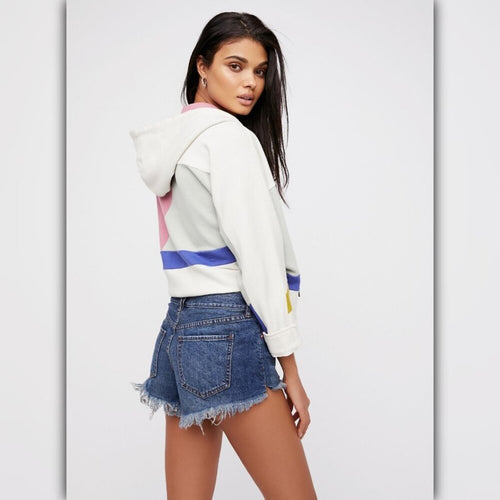 Woman wearing a colorful hoodie and denim shorts on a white background