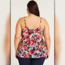 Woman wearing a colorful floral tank top on a plain background