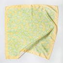 Yellow satin square scarf with green and pink daisy floral print and solid yellow border, laid flat.