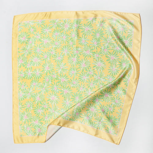 Yellow satin square scarf with green and pink daisy floral print and solid yellow border, laid flat.