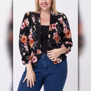 Front close view of plus size model wearing black floral blazer over a black top with blue jeans.