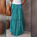 Person wearing a long green patterned skirt with a blurred background