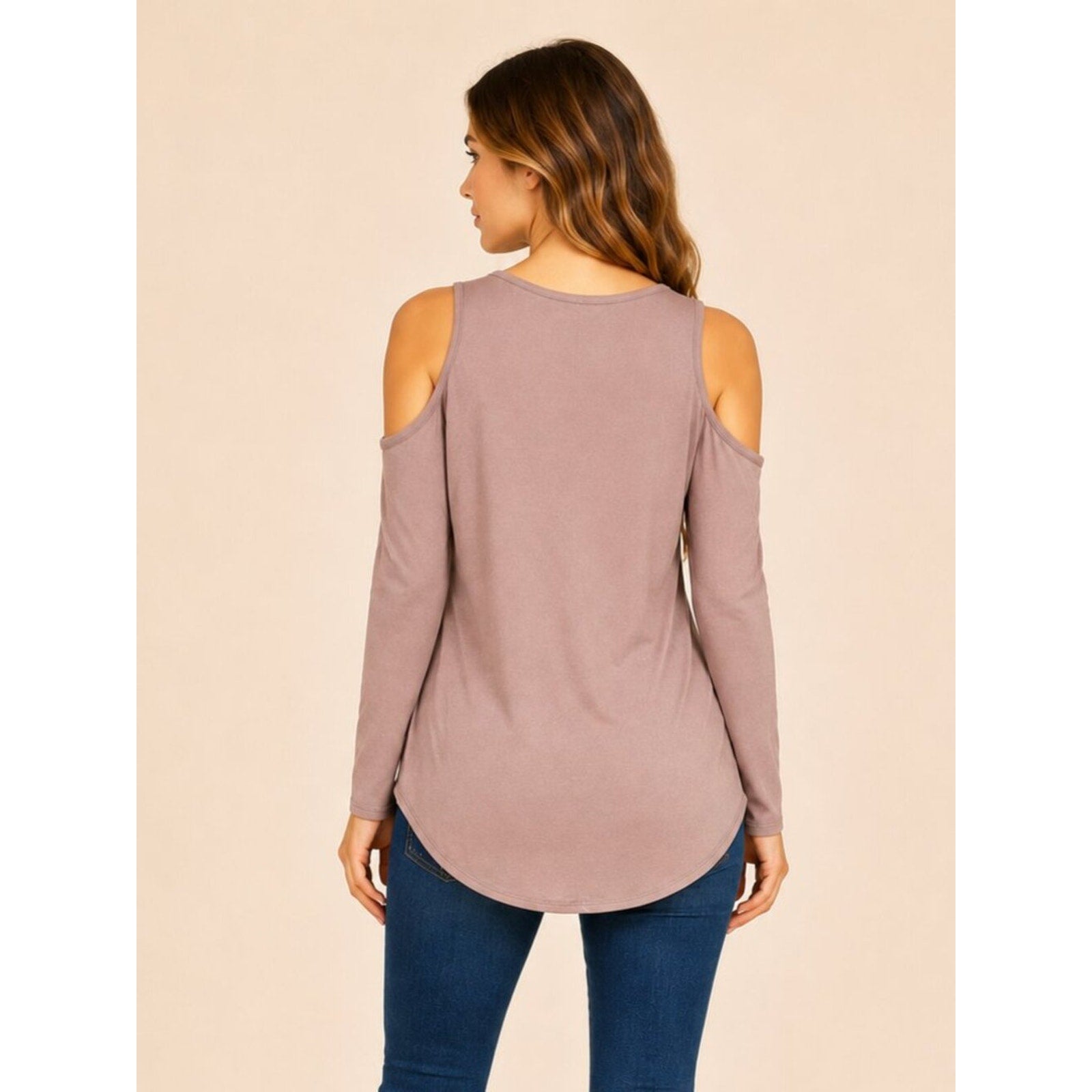 Woman wearing a mauve long-sleeve top with cold shoulder design on a beige background