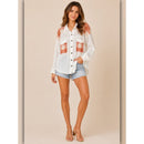 Woman wearing a white shirt with red pattern and denim shorts on a beige background