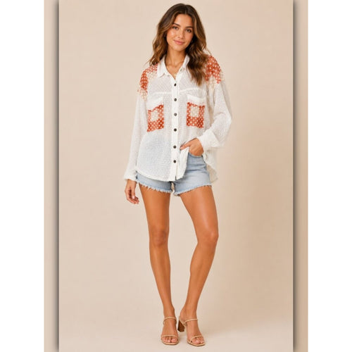 Woman wearing a white shirt with red pattern and denim shorts on a beige background