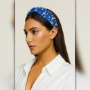 Woman wearing a blue headband with star decorations on a neutral background