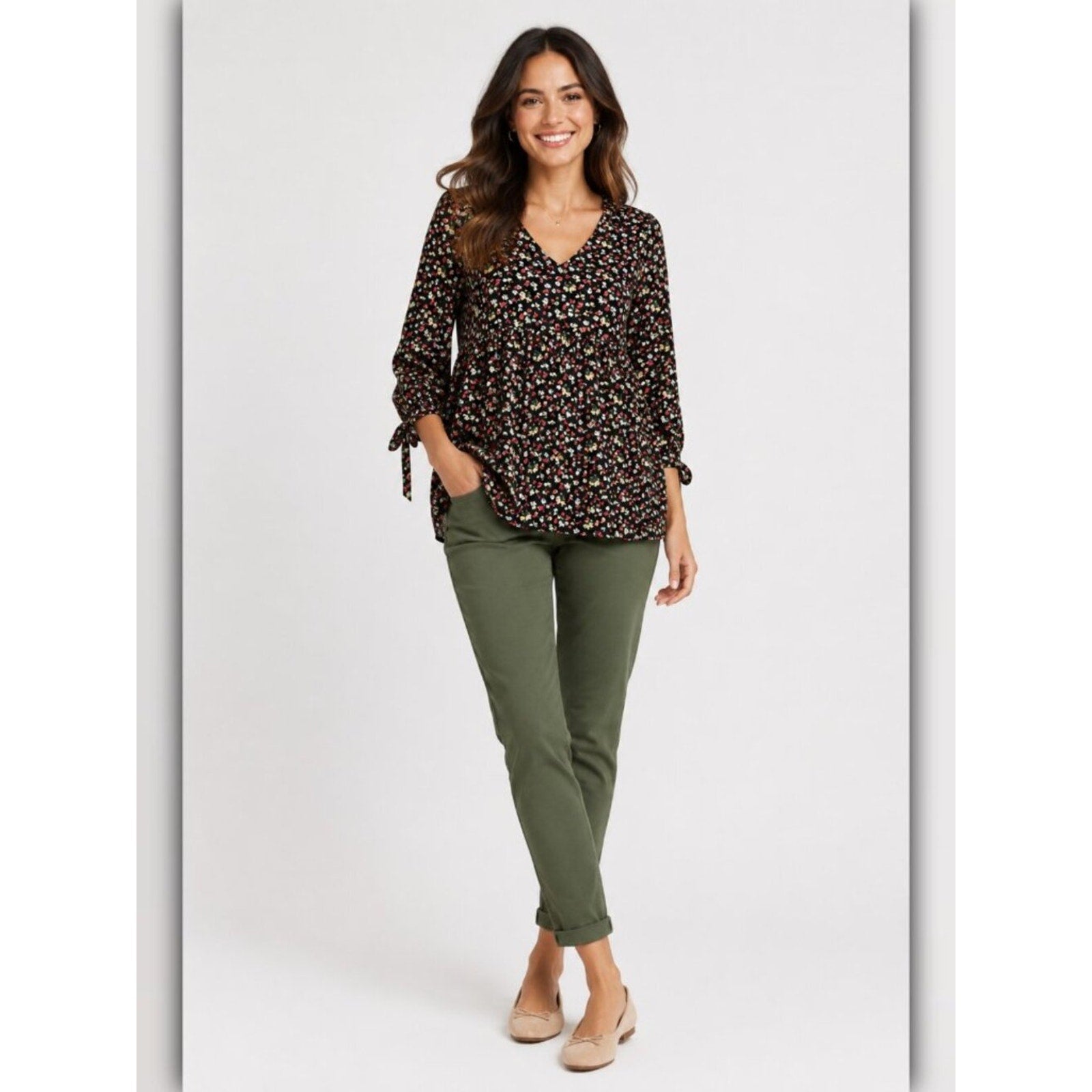 Woman wearing a patterned blouse and green pants on a white background