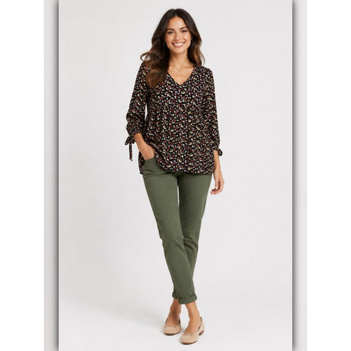 Woman wearing a patterned blouse and green pants on a white background