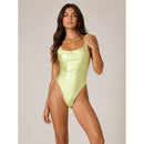Woman wearing a light green swimsuit against a neutral background