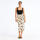Woman wearing a black top and patterned skirt on a white background