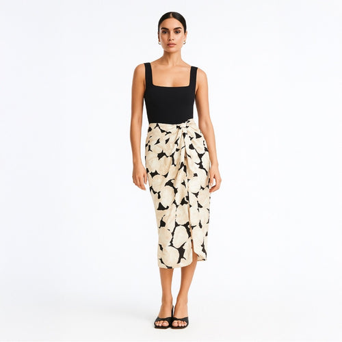 Woman wearing a black top and patterned skirt on a white background