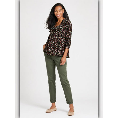 Woman wearing a patterned top and green pants on a white background