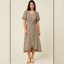A woman modeling a short-sleeve midi wrap dress with a beige and brown animal print pattern, featuring a V-neckline and a self-tie waist belt, set against a neutral beige background.