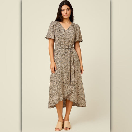 A woman modeling a short-sleeve midi wrap dress with a beige and brown animal print pattern, featuring a V-neckline and a self-tie waist belt, set against a neutral beige background.