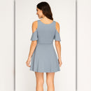 Woman wearing a light blue dress with cut-out shoulders on a white background