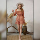 Woman in a floral dress standing in a rustic setting with decorative elements.
