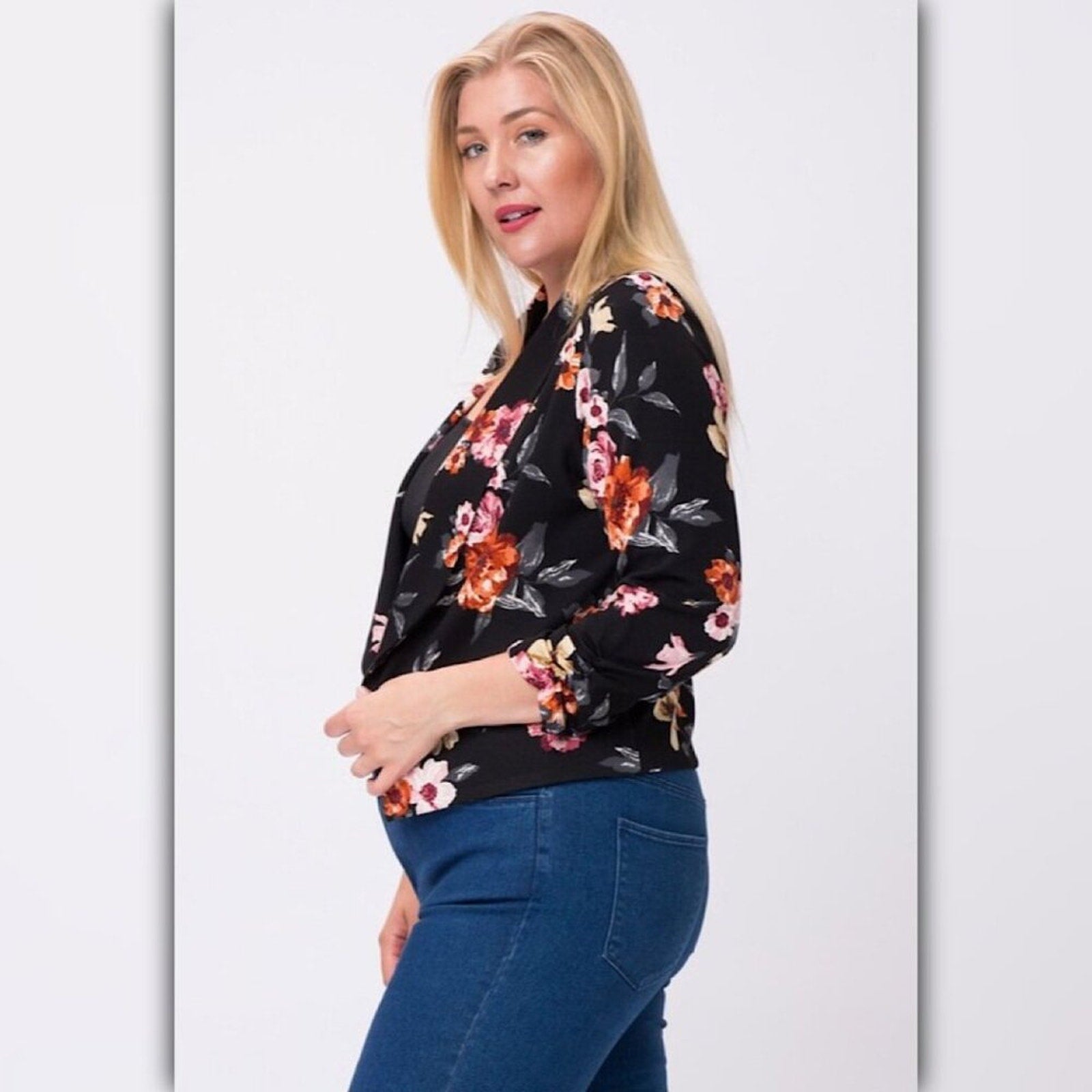 Side view of black floral open front blazer showing cropped fit, 3/4 sleeves, and curved front hem.