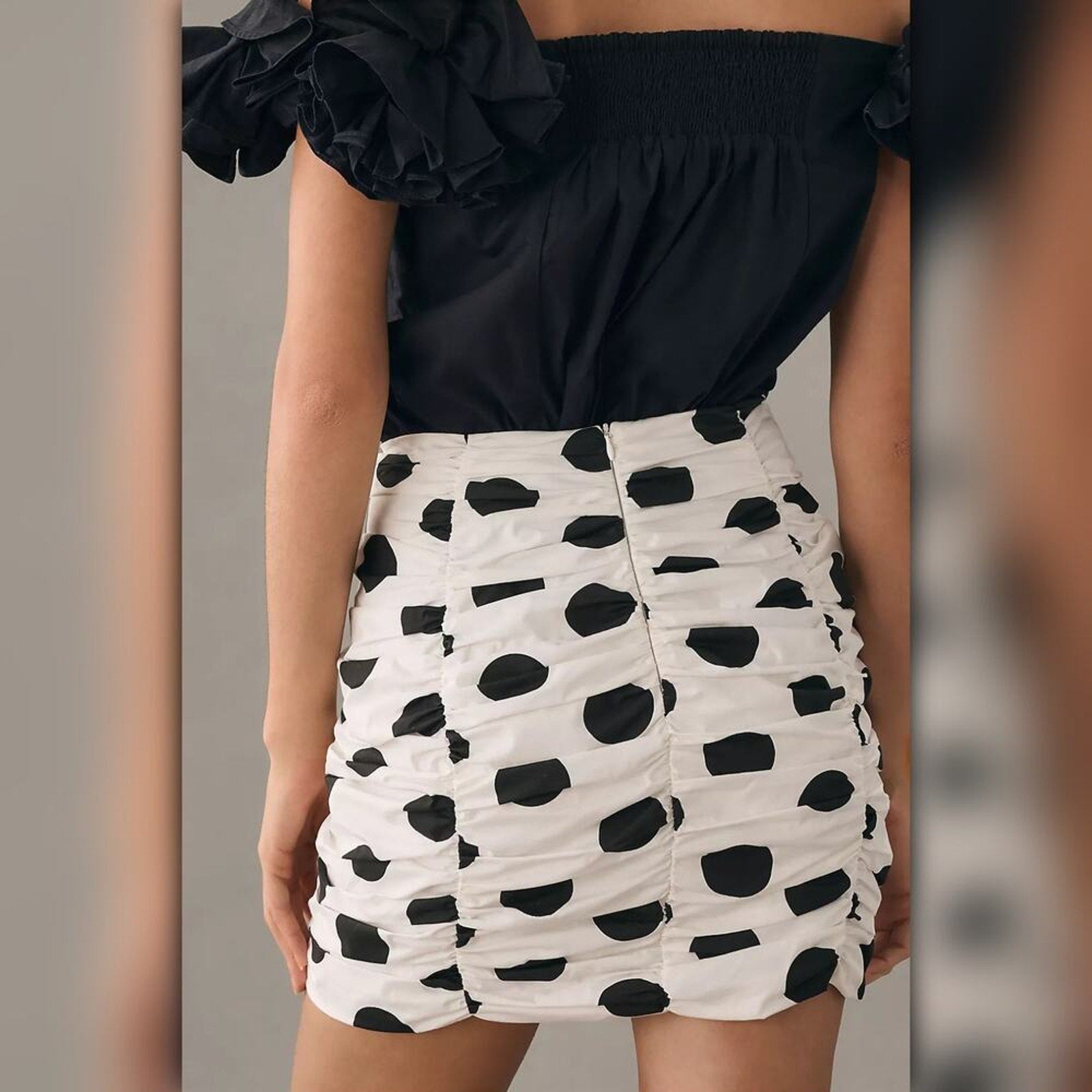 Person wearing a black top and white skirt with black polka dots.