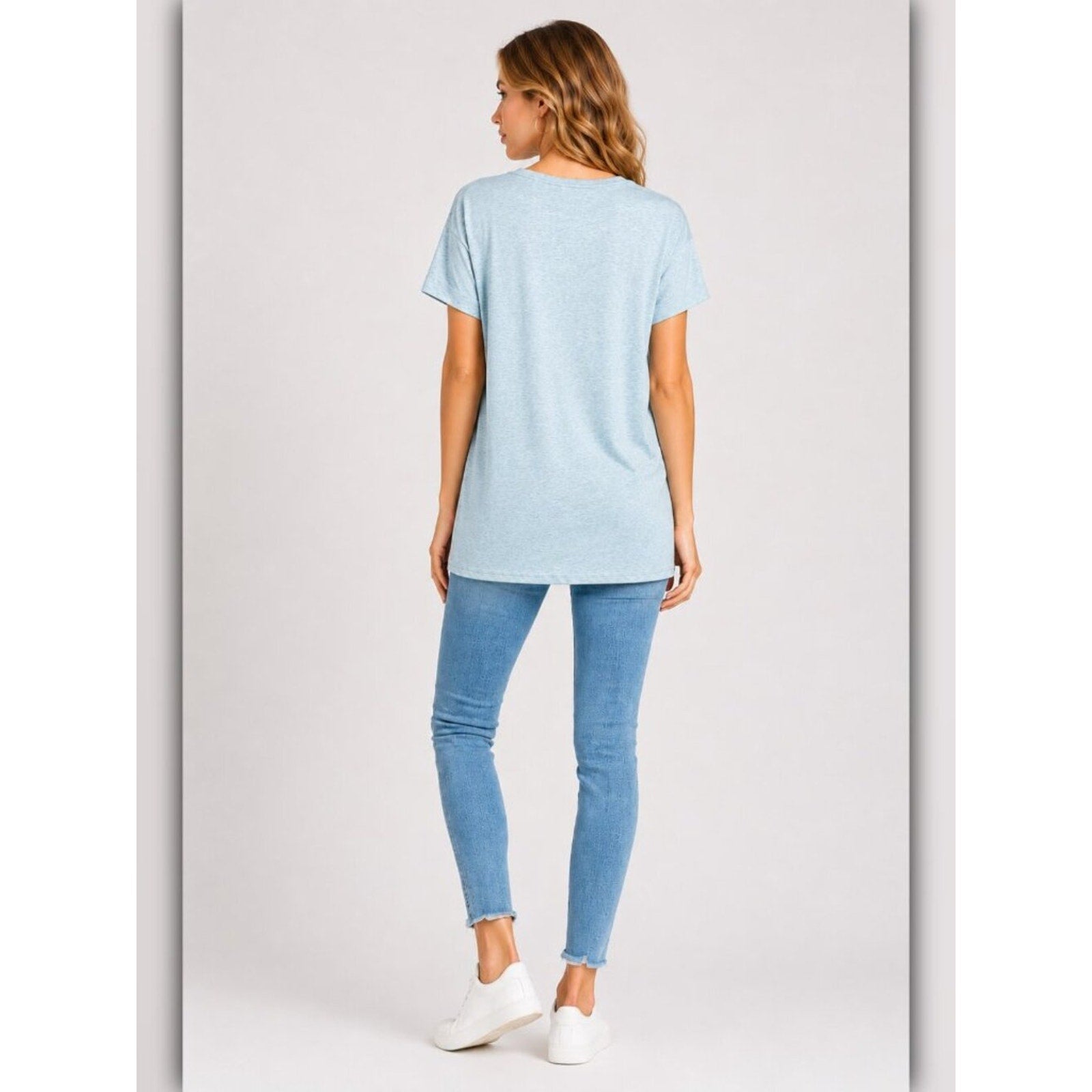 Woman wearing a light blue t-shirt and jeans on a white background