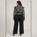 Woman wearing a zebra print blouse and black pants on a plain background