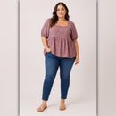 Woman wearing a plaid top and blue jeans on a light gray background
