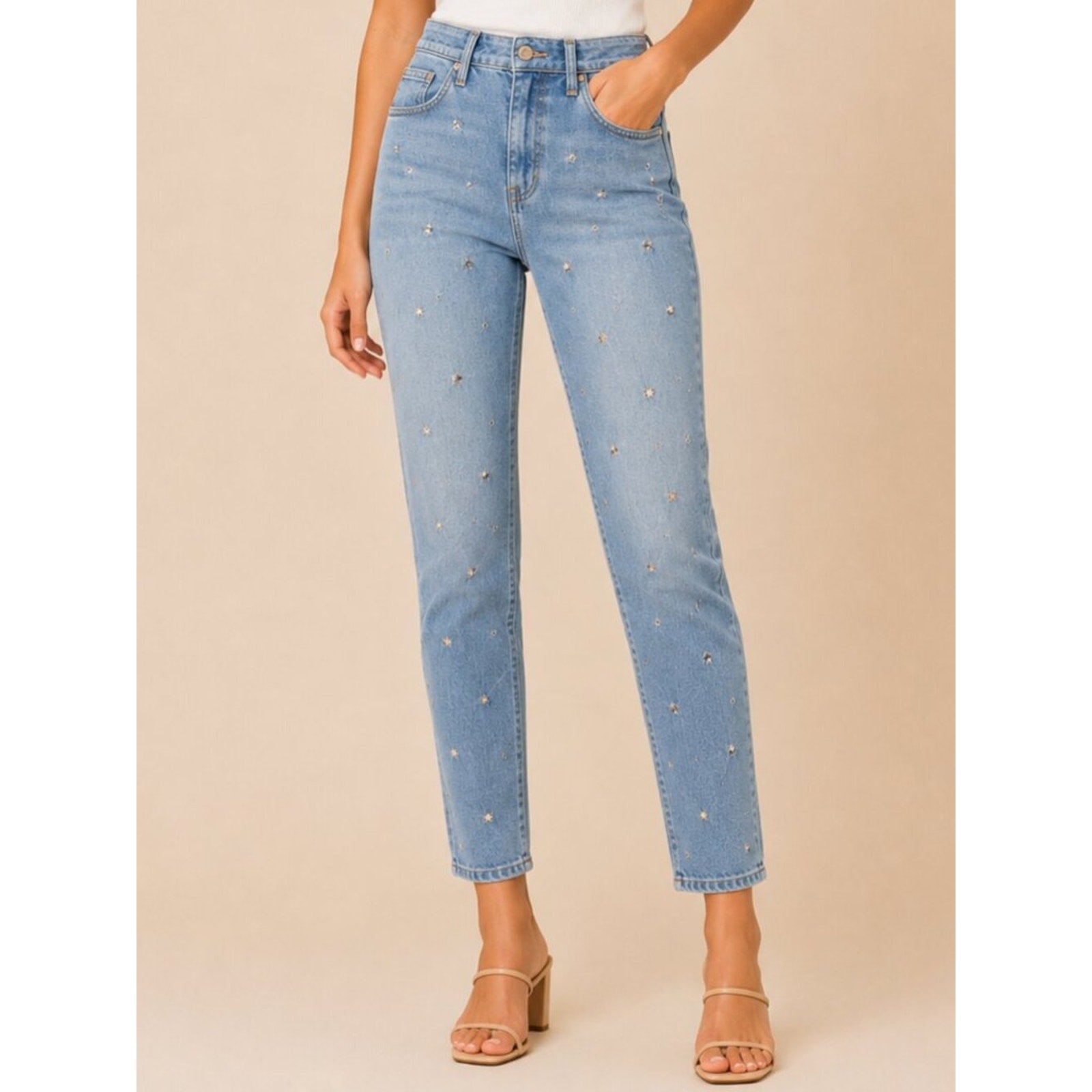 Light blue jeans with rhinestone embellishments on a beige background