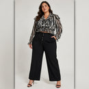 Woman wearing a zebra print blouse and black pants on a plain background