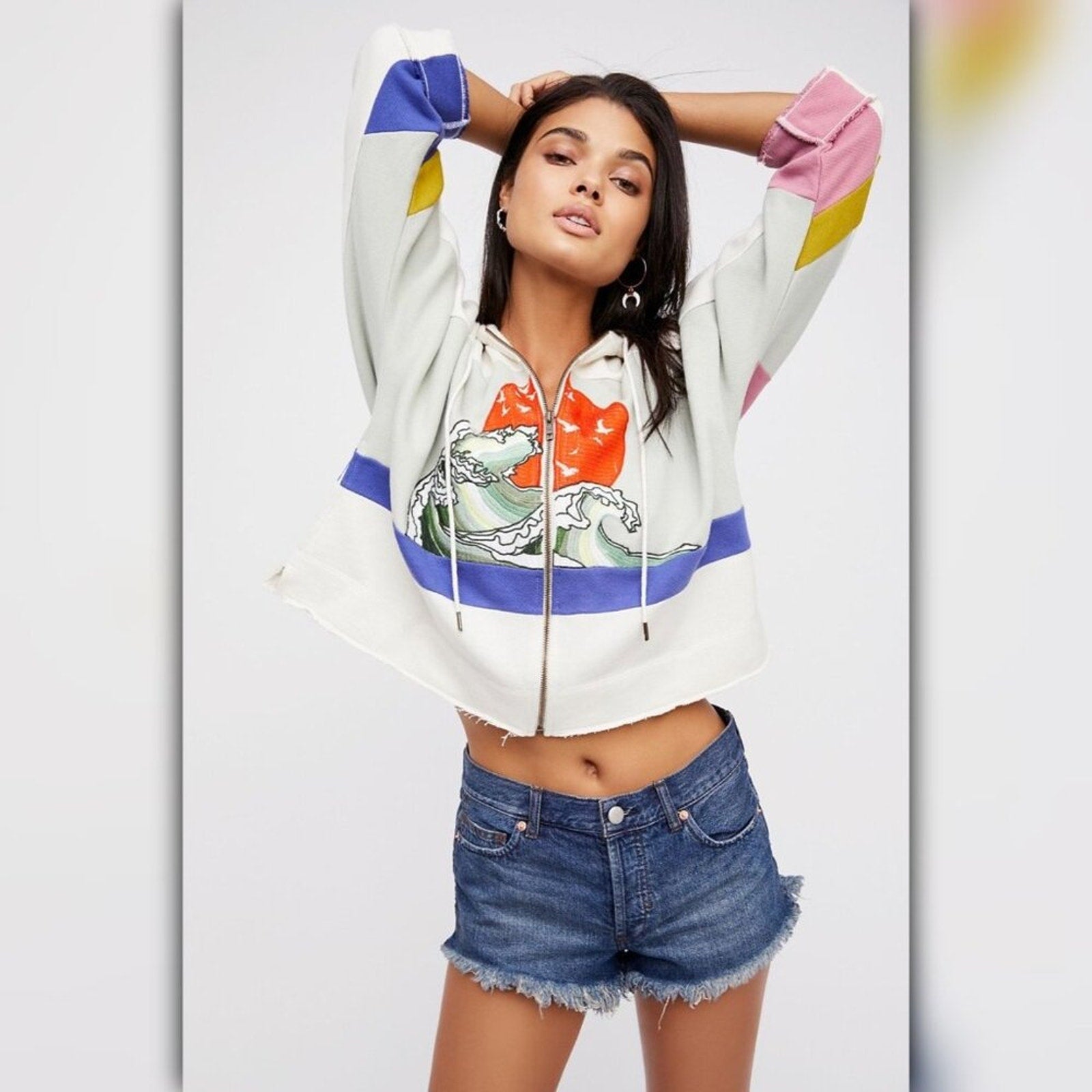 Woman wearing a colorful hoodie with a graphic design on a plain background