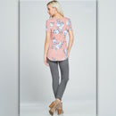 Woman wearing a pink floral top and gray pants on a light gray background