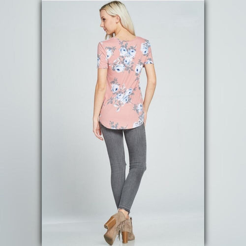 Woman wearing a pink floral top and gray pants on a light gray background