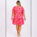 Woman wearing a pink and orange patterned dress on a light gray background