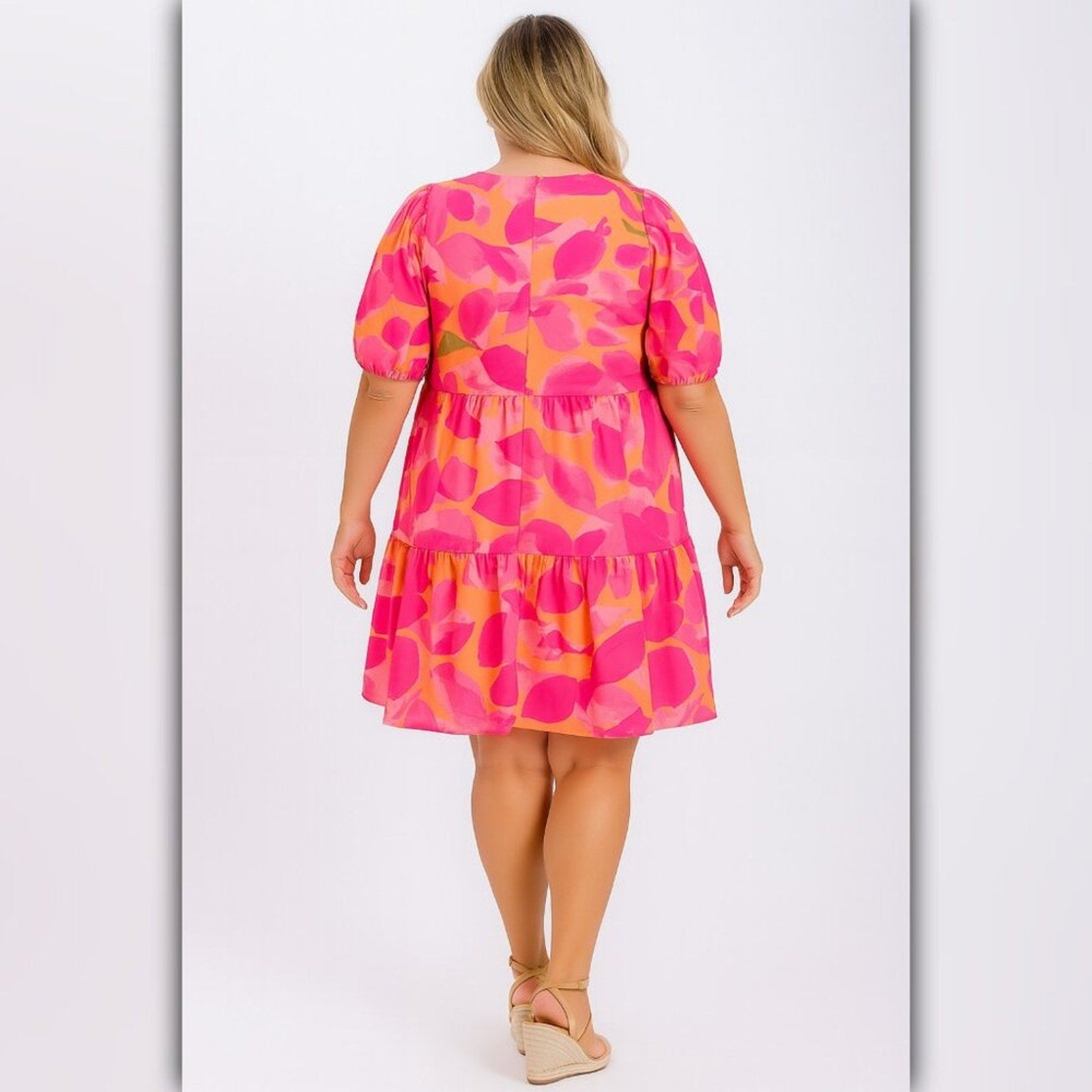 Woman wearing a pink and orange patterned dress on a light gray background