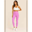 Woman wearing pink leggings and a white sports bra on a beige background