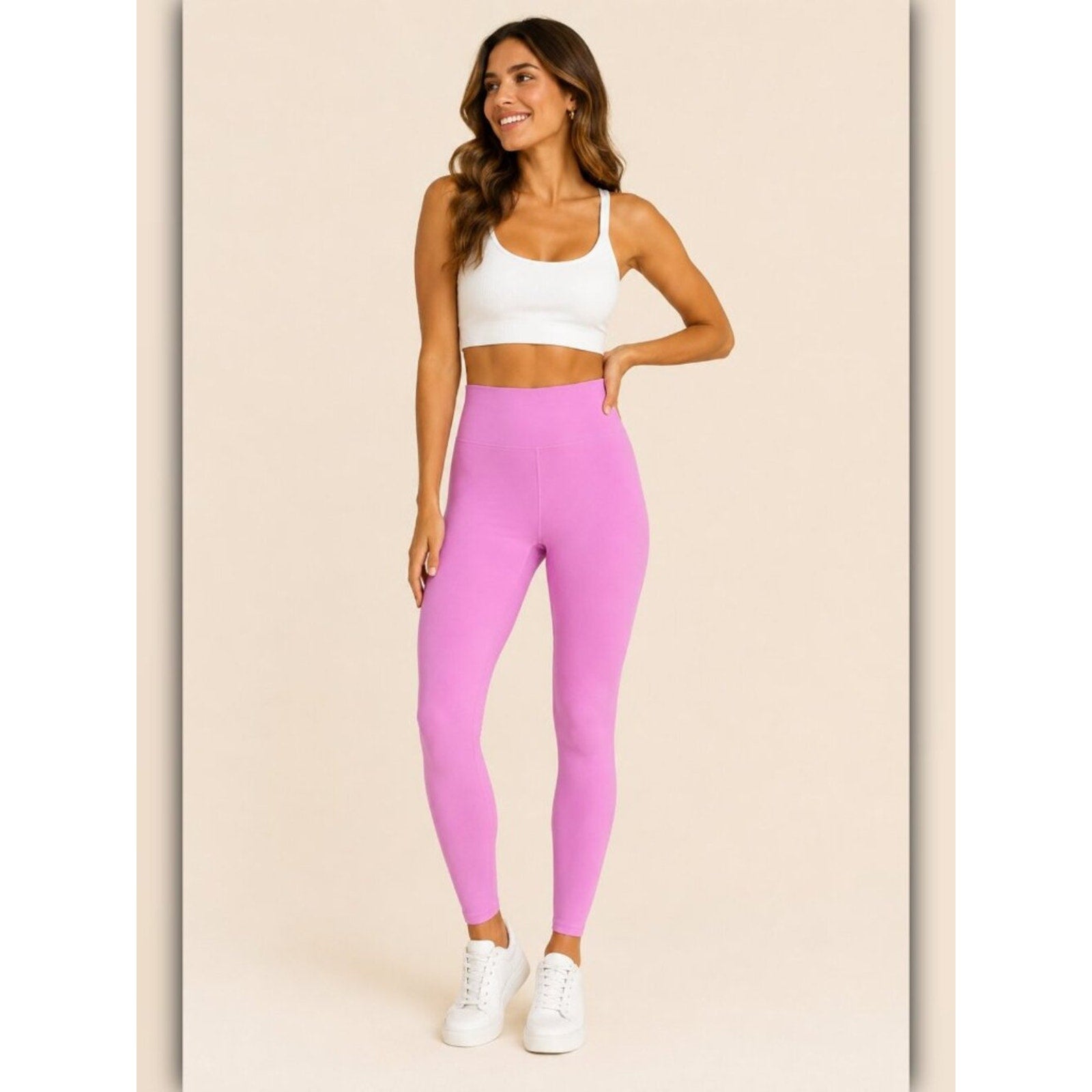 Woman wearing pink leggings and a white sports bra on a beige background