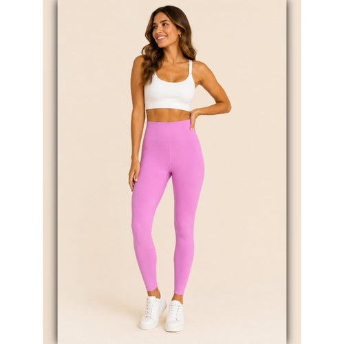 Woman wearing pink leggings and a white sports bra on a beige background