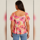 Woman wearing a colorful floral top with a plain background