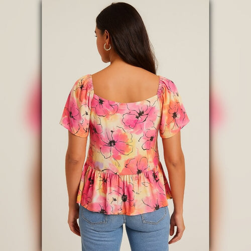 Woman wearing a colorful floral top with a plain background