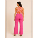 Woman wearing a bright pink jumpsuit with an orange floral top on a beige background